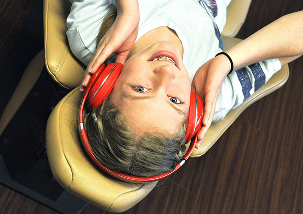 Patient wearing red headphones lies back in orthodontic chair during dental examination.