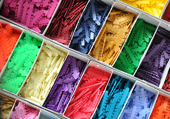 Colorful pigment powders arranged in compartmented storage boxes displaying vibrant rainbow hues.