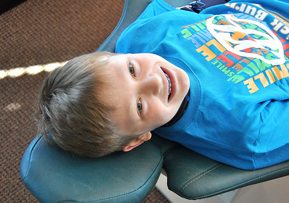 Young child lying on blue orthodontic pillow during dental examination at orthodontics office.