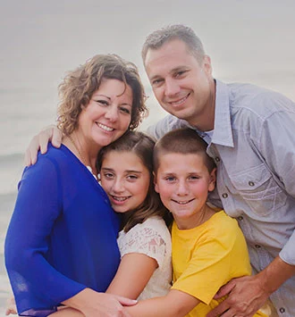 Family of four smiling together at beach portrait for orthodontics practice website
